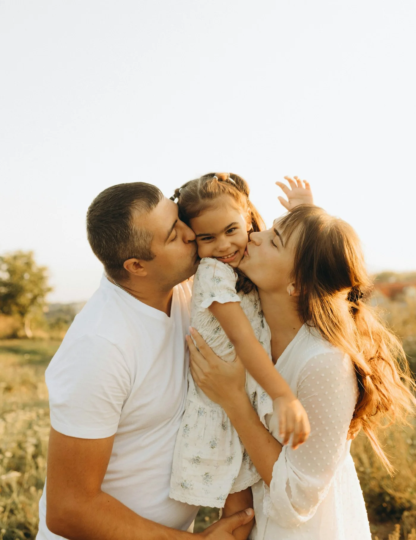 Una familia abrazando a su hija al aire libre